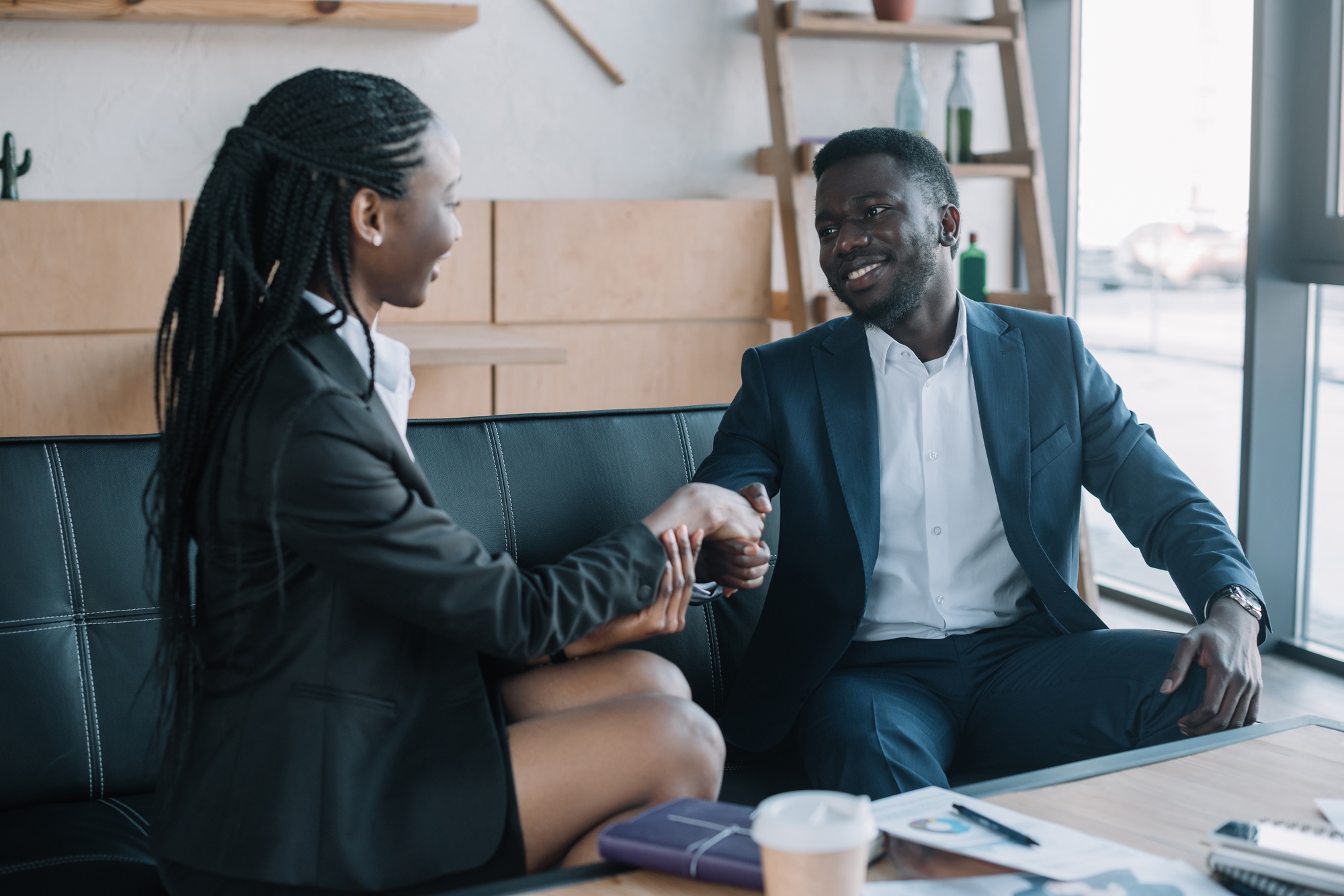 african american business partners shaking hands during meeting in cafe